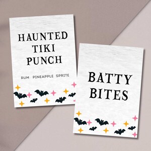 May include: Two white rectangular signs with black text. One reads "HAUNTED TIKI PUNCH" and the other "BATTY BITES". Both have a border of bats, stars, and orange and pink accents, perfect for Halloween.