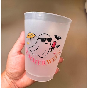 May include: A frosted plastic cup with a "SUMMERWEEN" design. The design features a cartoon ghost wearing sunglasses and holding a popsicle, with a yellow umbrella and bats. The text is in pink and gold.