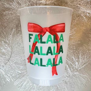 以下が含まれることがあります： 赤いリボンと「Falala Lalala Lalala」という文字が印刷された白いプラスチックカップです。