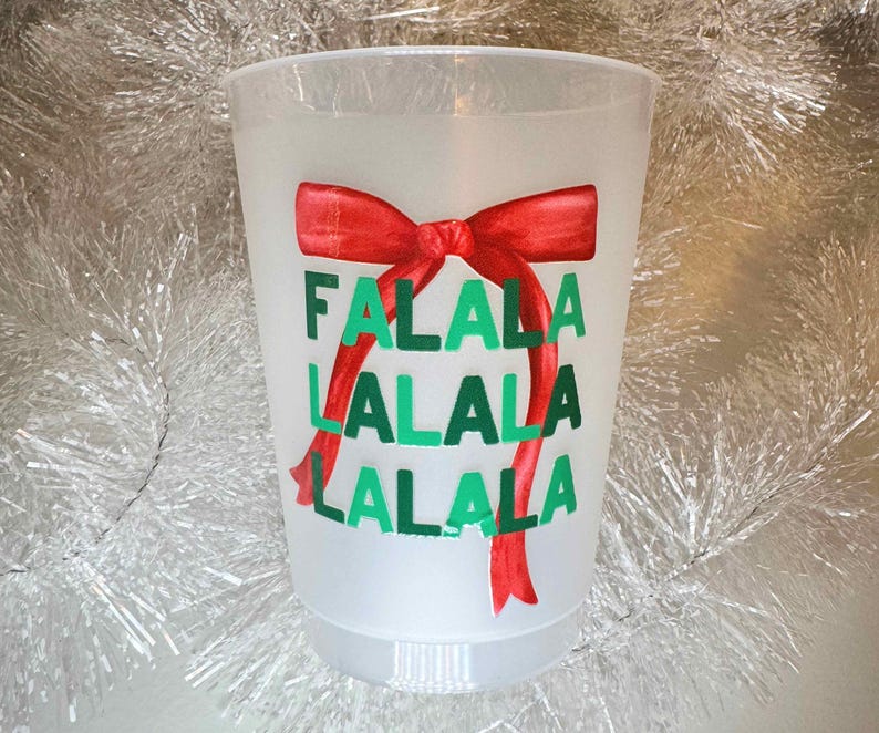 以下が含まれることがあります： 赤いリボンと「Falala Lalala Lalala」という文字が印刷された白いプラスチックカップです。