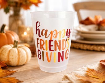 May include: A frosted plastic cup featuring the text "happy FRIENDS GIVING" printed in a gradient of red, orange, and yellow letters. The cup has a wide rim and a tapered base, designed for serving beverages during autumn holiday gatherings.