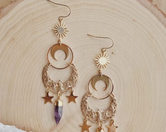 Puede incluir: Un par de pendientes colgantes de tono dorado con un dije de sol en la parte superior, una luna creciente, una luna creciente de filigrana ornamentada, dos dijes de estrella pequeños y un colgante de cristal amatista morado.