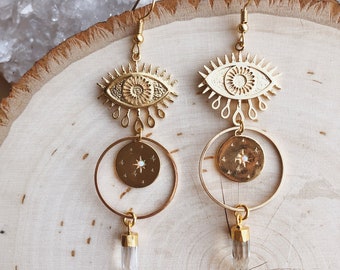 May include: Gold tone earrings with a detailed eye design, a circle with a star, and a clear crystal point pendant.