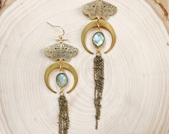 May include: Gold tone earrings with a crescent moon design, a gemstone, and a dangling chain. The earrings feature a detailed moth design.