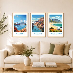 a cozy living room with a white sofa, a coffee table, and three framed posters of different cities hanging on the wall above the sofa.
