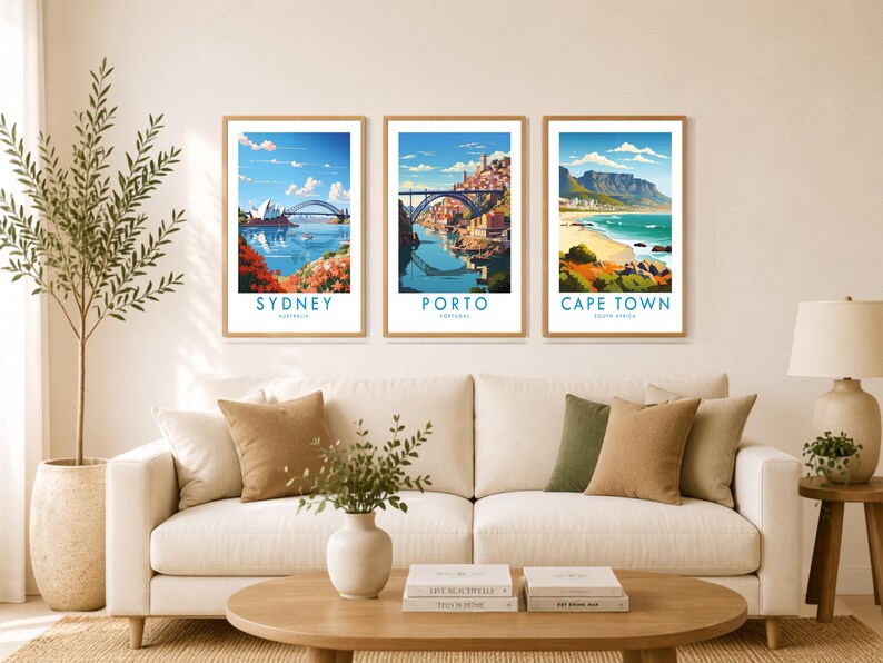 a cozy living room with a white sofa, a coffee table, and three framed posters of different cities hanging on the wall above the sofa.