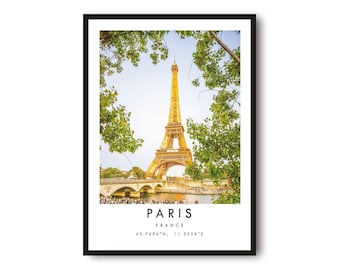 May include: Framed print featuring the Eiffel Tower in Paris, France, with a bridge and lush greenery. The print includes the city name, country, and coordinates. The image is set against a bright sky.