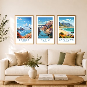 a cozy living room with a white sofa, a coffee table, and three framed posters of different cities hanging on the wall above the sofa.