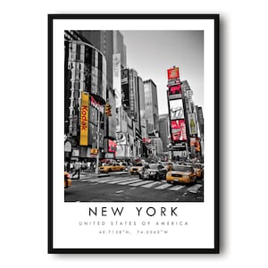 May include: A framed black and white photograph of Times Square in New York City, featuring yellow taxis, billboards, and tall buildings. The text "NEW YORK" and coordinates are printed at the bottom.