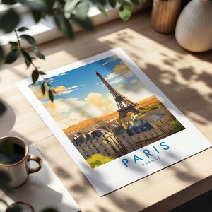 Op de afbeelding: Een rechthoekige kunstdruk met een kleurrijke illustratie van de Eiffeltoren boven Parijse gebouwen onder een helderblauwe lucht met zachte wolken. De tekst PARIS FRANCE staat in blauw gedrukt onderaan de witte rand.