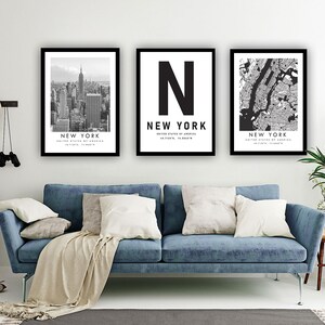 a living room with a blue sofa, a potted plant, and three framed pictures of New York City.