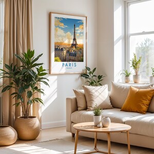 Op de afbeelding: Een ingelijste kunstdruk met een kleurrijke illustratie van de Eiffeltoren in Parijs, Frankrijk. Het kunstwerk toont een zonsondergang met wolken boven de skyline van de stad, met de tekst PARIS FRANCE in blauw gedrukt onderaan de lijst.