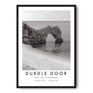May include: Black and white framed print featuring Durdle Door, a natural limestone arch in Dorset, United Kingdom. The print includes the text "DURDLE DOOR UNITED KINGDOM" and coordinates. A serene coastal landscape.