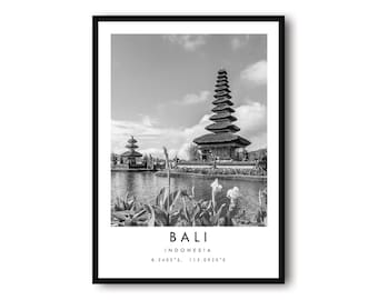 May include: Black and white framed print featuring a Balinese temple complex. The image shows a tiered structure reflected in the water, with text at the bottom reading "BALI INDONESIA" and coordinates. The sky is cloudy.