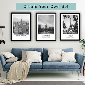 a living room with a blue sofa, a potted plant, and three framed pictures of famous landmarks in New York, London, and Paris.