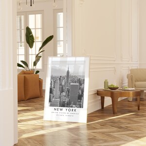 a large framed poster of the New York City skyline, with a wooden coffee table in the foreground and a beige sofa in the background.