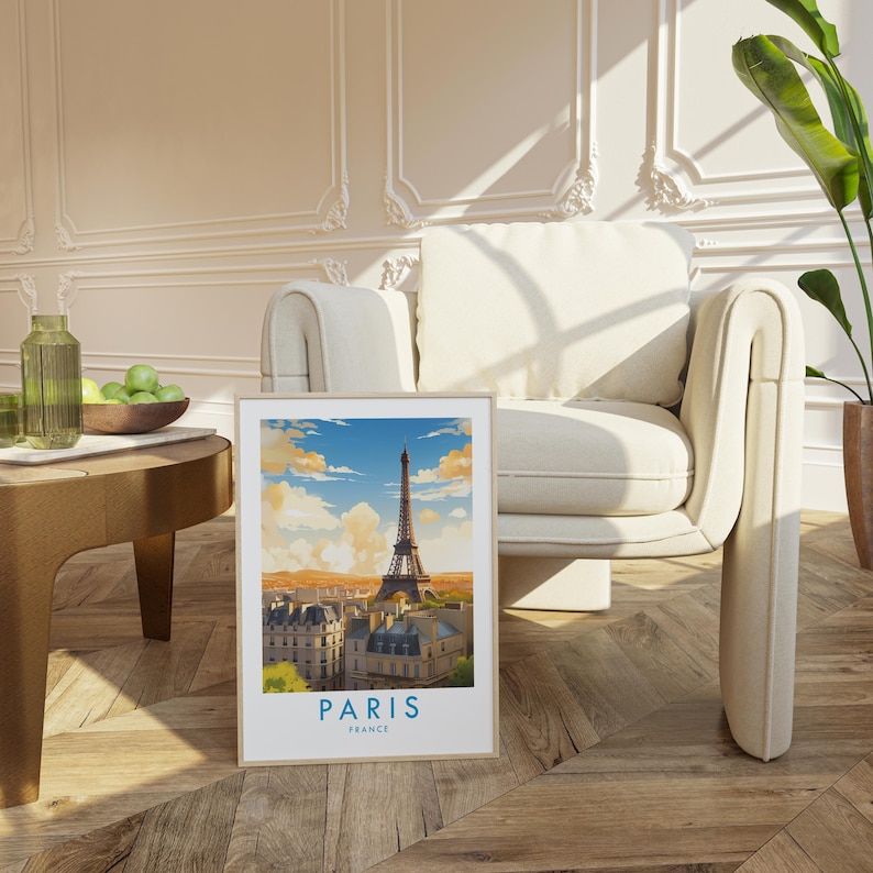 Op de afbeelding: Een ingelijste verticale kunstdruk met een gestileerde illustratie van de Eiffeltoren in Parijs, Frankrijk. De afbeelding toont een stadsgezicht onder een blauwe lucht met wolken, met de tekst PARIS FRANCE in het blauw onderaan de print.