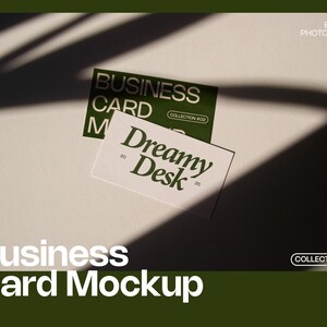 Op de afbeelding: Een mockup van een visitekaartje met twee kaarten op een wit oppervlak met schaduwen. E&eacute;n kaart is groen met de tekst "BUSINESS CARD" en "COLLECTION #02". De andere kaart is wit met "Dreamy Desk" erop gedrukt. De tekst "Business Card Mockup" staat onderaan.