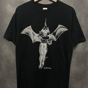 May include: Black t-shirt with a white graphic print of a winged demon with a pointed tail. The text "Dynamic Planning" is printed below the demon.