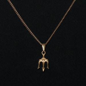 May include: A gold chain necklace with a trident pendant. The chain is thin and delicate, and the pendant is small and detailed.