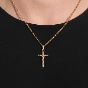 May include: A gold chain necklace with a small gold crucifix pendant.