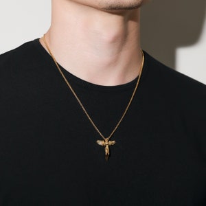 May include: A gold chain necklace with a pendant featuring a detailed angel figure with wings.