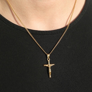 May include: A gold chain necklace with a gold Jesus crucifix pendant.
