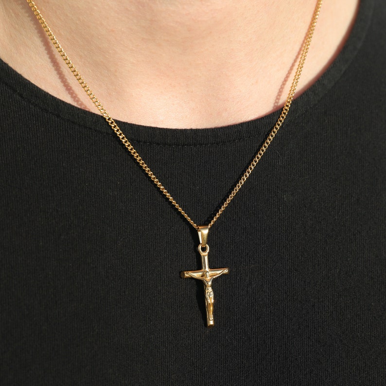 May include: A gold chain necklace with a gold Jesus crucifix pendant.