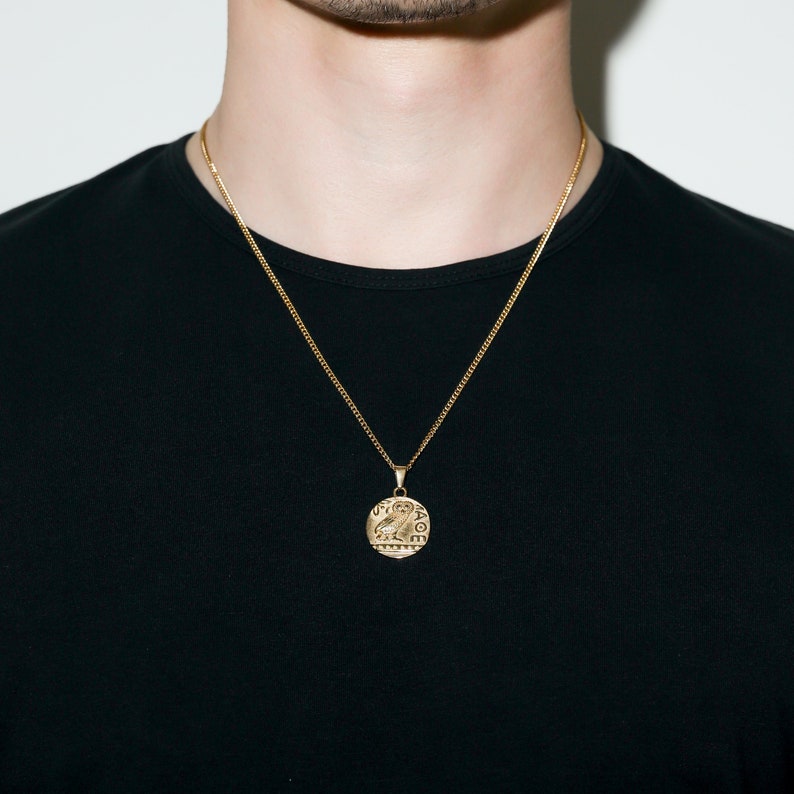 May include: A gold chain necklace with a round pendant featuring an owl design. The pendant has intricate details and the word "LOVE" inscribed around the edge.