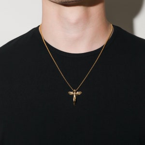 May include: A gold chain necklace with a pendant featuring a winged angel figure.