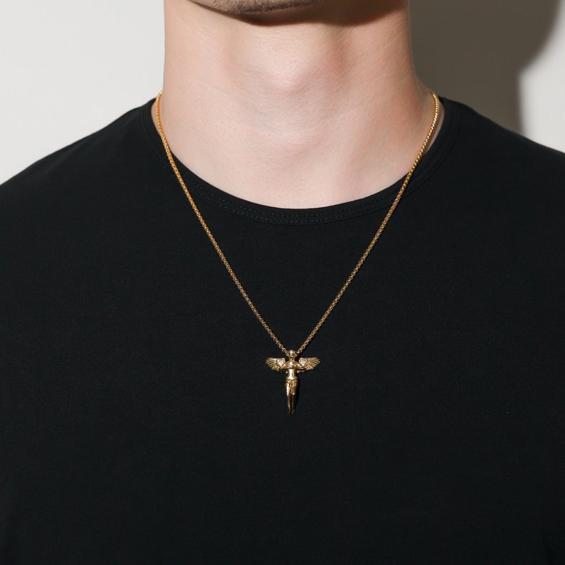 May include: A gold chain necklace with a pendant featuring a winged angel figure.