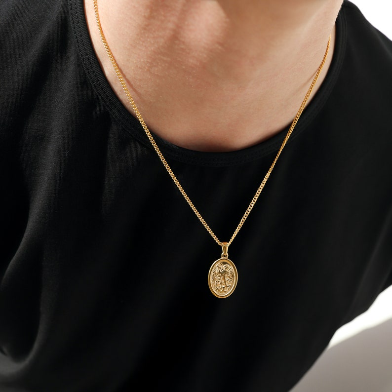 May include: A gold chain necklace with a gold oval pendant featuring a detailed design.
