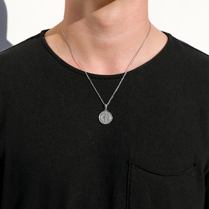 May include: A silver chain necklace with a round pendant featuring a compass design.