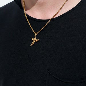 Puede incluir: Un collar de cadena de oro con un peque&ntilde;o colgante de &aacute;ngel. La cadena es de estilo cuerda y el colgante es detallado.