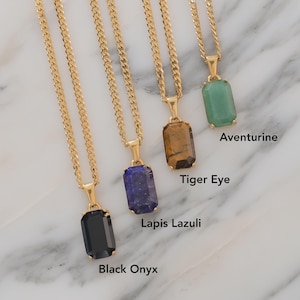 Peut inclure: Quatre colliers dorés avec des pendentifs rectangulaires en pierres précieuses. Les pierres sont de l'onyx noir, du lapis-lazuli, de l'œil de tigre et de l'aventurine. Les pendentifs sont suspendus à une chaîne dorée.