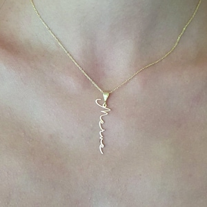 Könnte beinhalten: Eine goldene Kettenkette mit einem Anhänger, auf dem "Merve" in Kursivschrift steht.