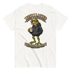 May include: A white t-shirt featuring a graphic of a green frog wearing a black hoodie and holding a white mug with a sad face. The text above the frog reads WISH I LACKED CRITICAL THINKING SKILLS and the text below reads Y'ALL SEEM SO HAPPY.