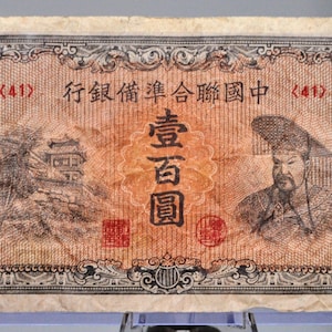 May include: An antique Chinese banknote with intricate designs and text. The note features a portrait of a man, a pagoda, and the number 100 in each corner. The text includes the denomination and other Chinese characters.