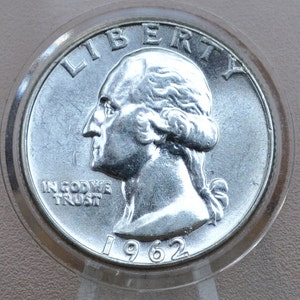 May include: A silver US quarter dollar coin with the year 1962, the words "LIBERTY" and "IN GOD WE TRUST", and a profile of George Washington.
