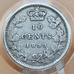 May include: A silver Canadian 10 cent coin from 1899. The coin features a wreath of maple leaves surrounding the denomination and the year of minting.