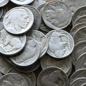 Peut inclure: Une collection de pièces de cinq cents américaines vintage de couleur argent, représentant le profil d'un Indien américain, un bison et les mots "United States of America" et "Five Cents".