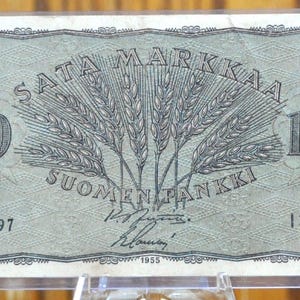 Könnte beinhalten: Eine alte 100 Markkaa Banknote aus Finnland mit dem Text "SATA MARKKAA" und "SUOMEN PANKKI". Die Banknote zeigt ein Weizenähren-Design und die Zahl "100" auf beiden Seiten. Die Seriennummer lautet 13665397.