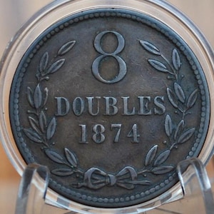 May include: A copper-coloured coin with a wreath of leaves surrounding the number "8" and the text "DOUBLES 1874".