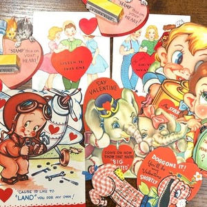 Puede incluir: Una colección de tarjetas de San Valentín vintage con varias ilustraciones. Las tarjetas presentan imágenes de niños, animales y aviones, con frases como "Stamp this on your heart!" y "Cause I'd like to land you for my own!"