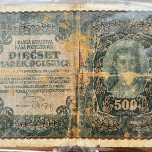 Puede incluir: Un antiguo billete polaco de 500 Marek, con texto y un retrato. El billete tiene un esquema de color verde y beige con diseños florales ornamentados y el número 500 en un lugar destacado.