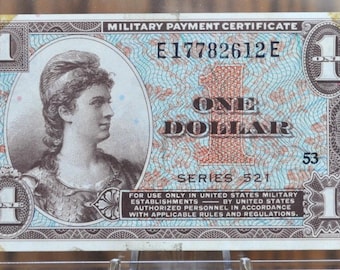 Peut inclure: Un certificat de paiement militaire bleu et blanc avec le texte "Military Payment Certificate", "E17782612E", "One Dollar", "Series 521" et "53". Le certificat présente le portrait d'une femme en robe blanche.