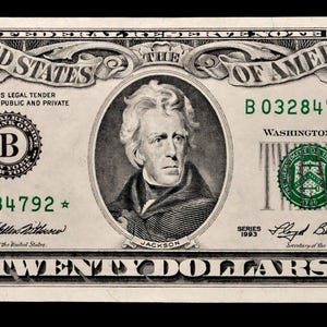Pode incluir: Uma nota de vinte dólares com um retrato de Andrew Jackson. A nota inclui o texto "United States of America" e "Twenty Dollars". O número de série é B03284792*.