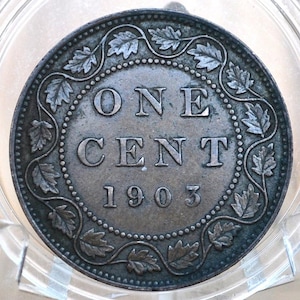 May include: A copper Canadian one cent coin from 1903. The coin features a wreath of maple leaves around the inscription "ONE CENT 1903".