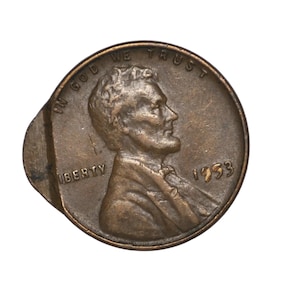 Puede incluir: Una moneda de un centavo de Lincoln de 1953 de color cobre con un error de acuñación descentrado. El anverso muestra el perfil de Abraham Lincoln, el texto IN GOD WE TRUST, LIBERTY y el año 1953, con un corte metálico en el lado izquierdo.
