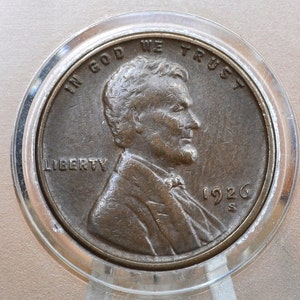 May include: A copper-coloured 1926 Lincoln penny with the inscription "In God We Trust" and "Liberty" on the obverse side. The coin features a profile of Abraham Lincoln and the letter "S" below the date.